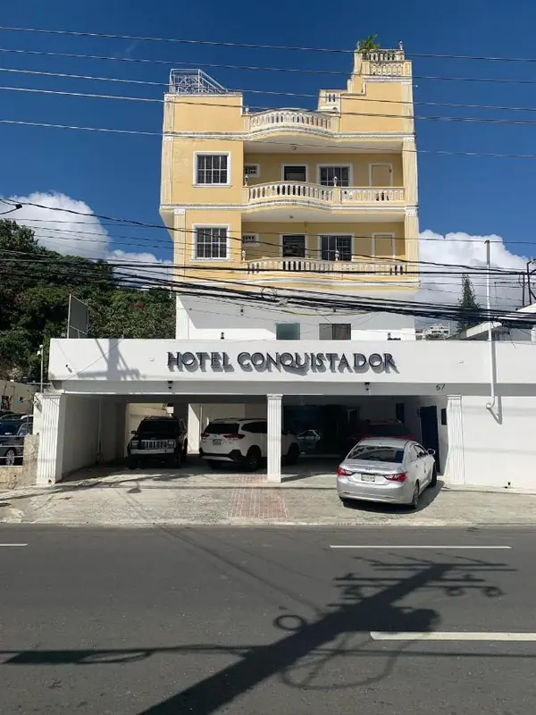 The front of Hotel Conquistador, a yellow building with balconies and the hotel sign above the garage